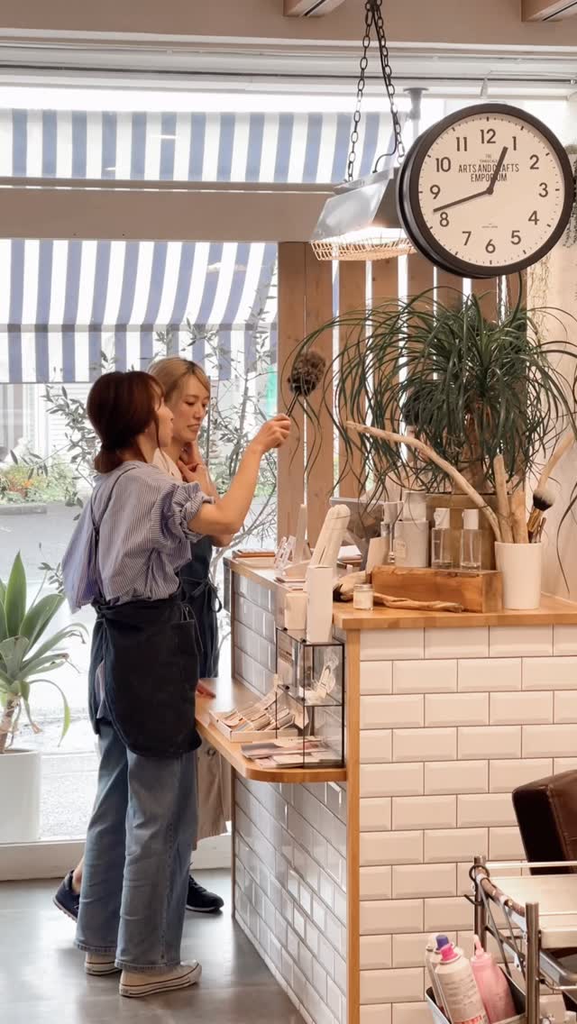 白いタイルとグリーンに囲まれたhair salon BEACHの店内で談笑するスタッフ